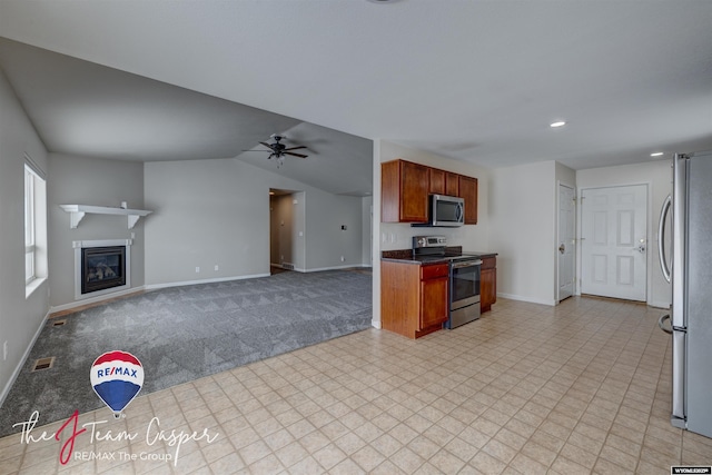 kitchen featuring appliances with stainless steel finishes, ceiling fan, light carpet, and lofted ceiling