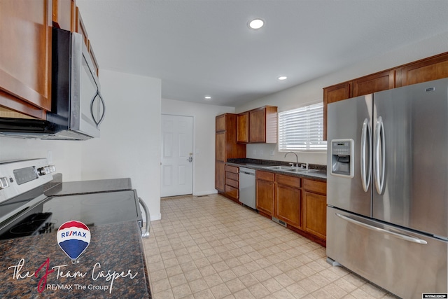 kitchen featuring sink, appliances with stainless steel finishes, and dark stone countertops