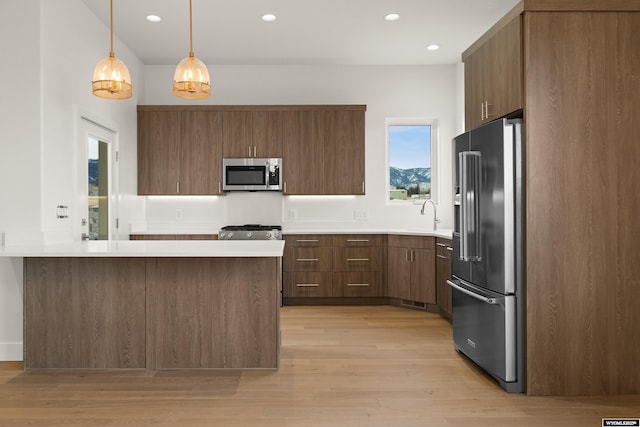 kitchen with high end refrigerator, range, stainless steel microwave, a peninsula, and light countertops