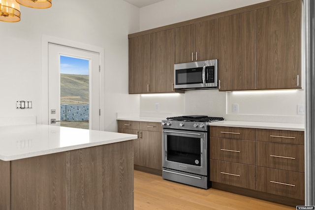 kitchen featuring light wood-type flooring, modern cabinets, appliances with stainless steel finishes, and light countertops