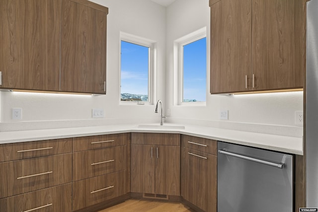 kitchen with stainless steel dishwasher, modern cabinets, light countertops, and a sink