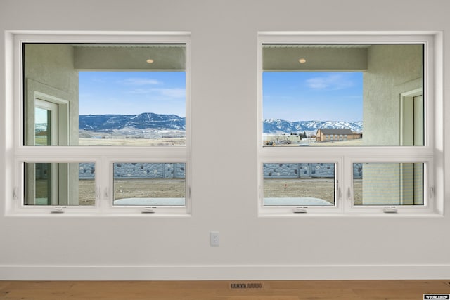 interior space featuring visible vents, a mountain view, baseboards, and wood finished floors