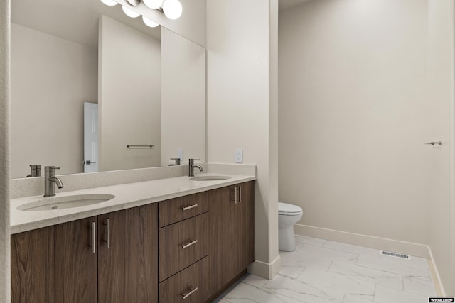 bathroom with marble finish floor, a sink, baseboards, and double vanity