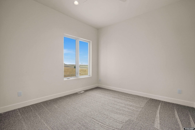 empty room with baseboards, visible vents, and dark carpet