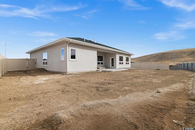 rear view of property with a fenced backyard, a patio, and stucco siding