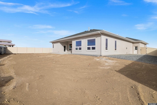 back of property with a fenced backyard and stucco siding