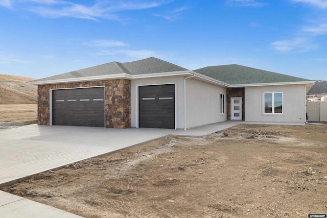 view of front of house with a garage, stone siding, a shingled roof, and driveway