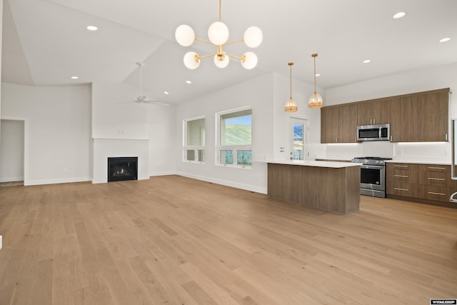 kitchen with ceiling fan with notable chandelier, light countertops, appliances with stainless steel finishes, and light wood-style flooring