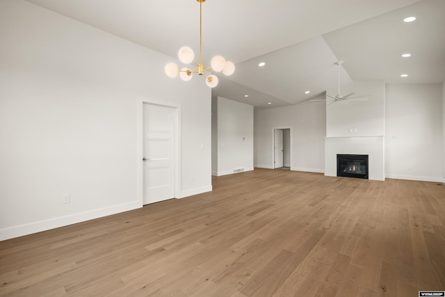 unfurnished living room featuring light wood-type flooring, a glass covered fireplace, baseboards, and ceiling fan with notable chandelier