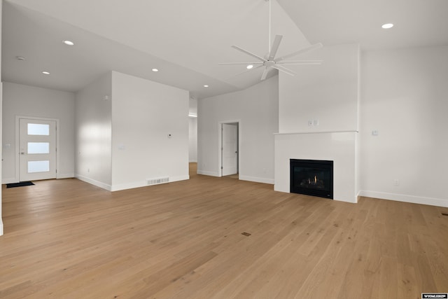 unfurnished living room featuring visible vents, a ceiling fan, light wood-style flooring, a lit fireplace, and recessed lighting