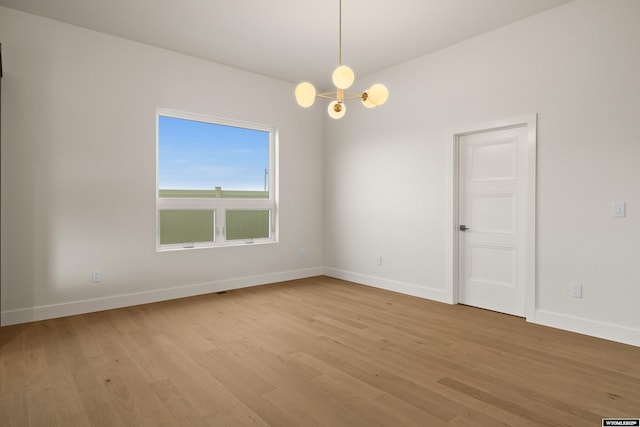 unfurnished room featuring a chandelier, baseboards, and light wood-style floors