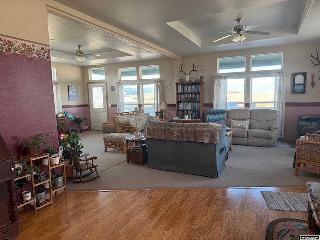 living room featuring a raised ceiling, light wood-type flooring, and plenty of natural light