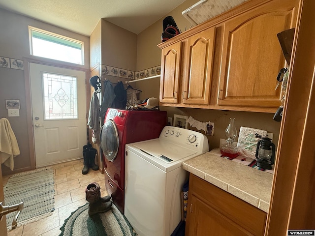 laundry room with light tile patterned floors, separate washer and dryer, cabinets, and a textured ceiling