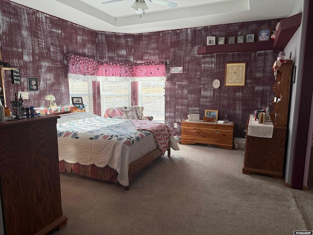 carpeted bedroom featuring a raised ceiling and ceiling fan