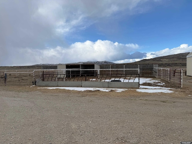 exterior space with a rural view, an outbuilding, and a mountain view