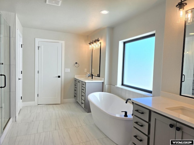 bathroom with a sink, two vanities, visible vents, a soaking tub, and a shower stall