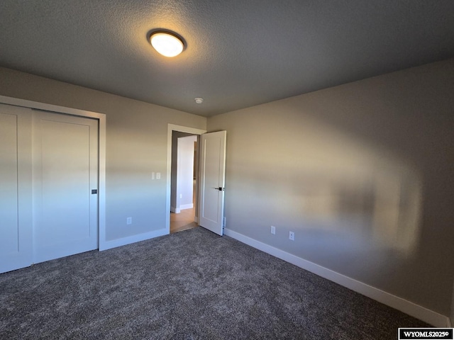 unfurnished bedroom with a textured ceiling, carpet floors, a closet, and baseboards