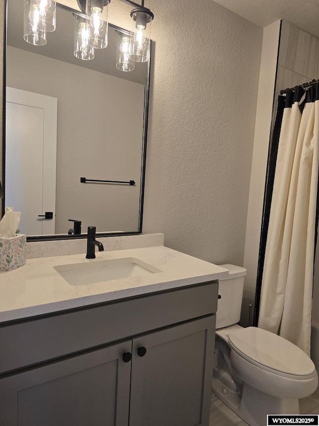 bathroom featuring a textured wall, vanity, toilet, and a shower with curtain