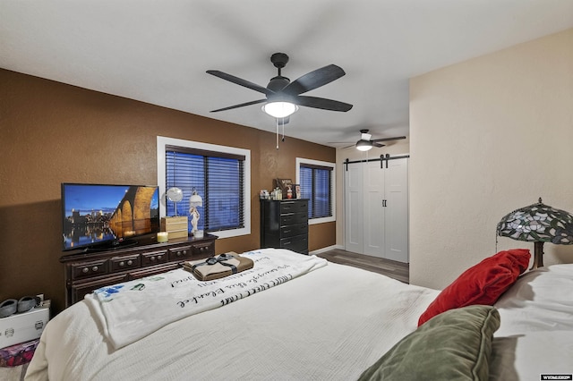 bedroom with ceiling fan and a barn door