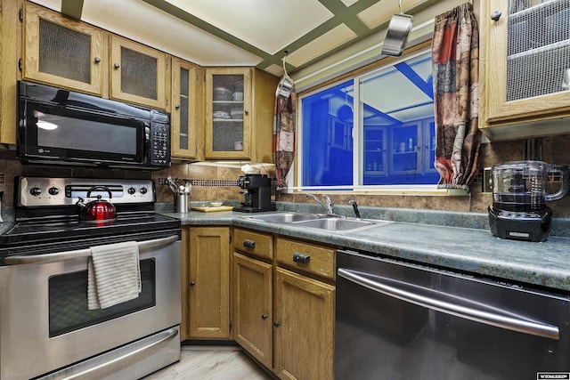 kitchen with sink, decorative backsplash, black appliances, and light hardwood / wood-style floors