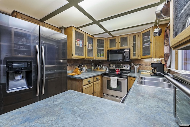 kitchen with coffered ceiling, appliances with stainless steel finishes, sink, and decorative backsplash