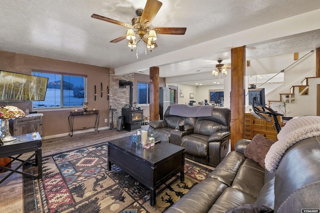 living room with a wood stove, hardwood / wood-style flooring, ceiling fan, and a textured ceiling