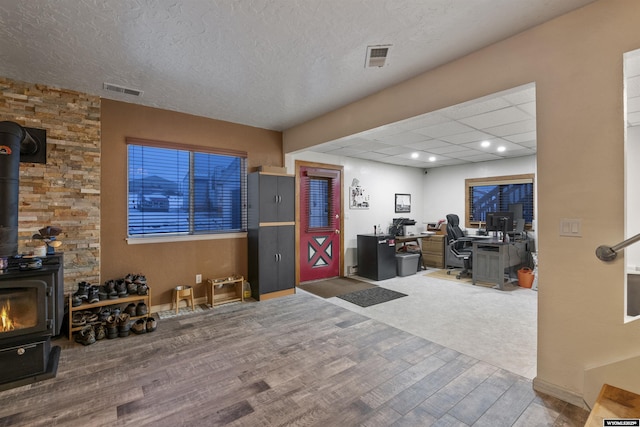 office area featuring a wood stove, wood-type flooring, and a textured ceiling