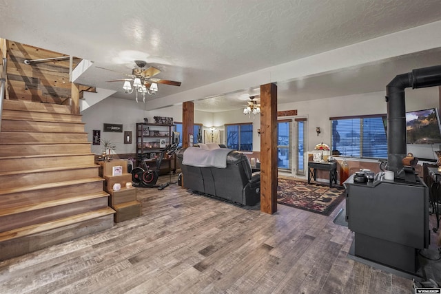 bedroom featuring hardwood / wood-style floors, a wood stove, ceiling fan, and a textured ceiling