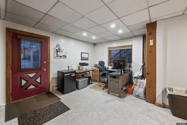 office area with a baseboard heating unit and a drop ceiling