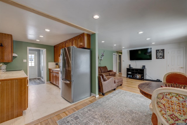 kitchen with exhaust hood, stainless steel refrigerator, and light hardwood / wood-style floors