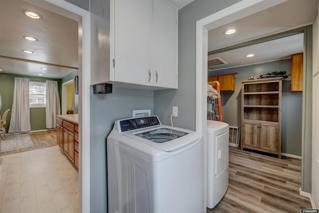 laundry room featuring washer and dryer, cabinets, and light hardwood / wood-style floors