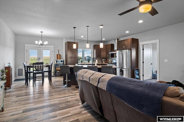 living room featuring recessed lighting, a textured ceiling, wood finished floors, baseboards, and ceiling fan with notable chandelier