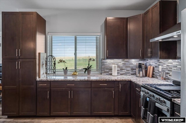 kitchen featuring light stone countertops, wall chimney range hood, stainless steel range with gas cooktop, and backsplash