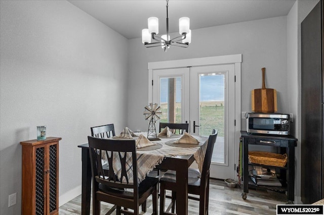 dining room with an inviting chandelier, baseboards, wood finished floors, and french doors