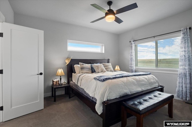 bedroom featuring ceiling fan, dark colored carpet, and multiple windows