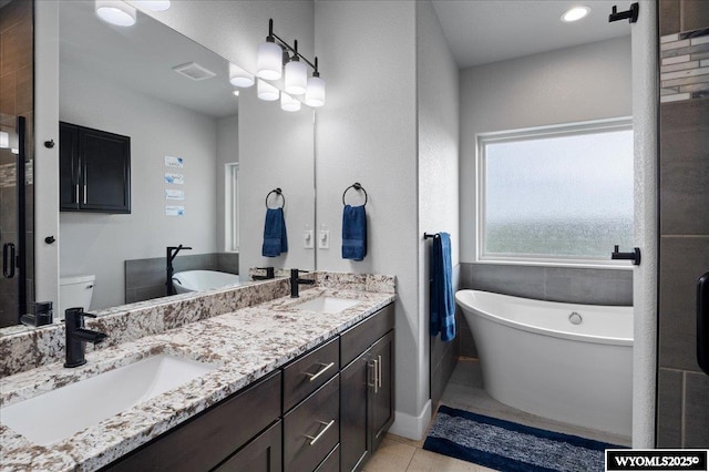 bathroom featuring tile patterned flooring, a soaking tub, a sink, and double vanity