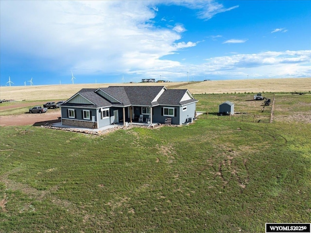 view of front of house with a shed, a front yard, and a rural view