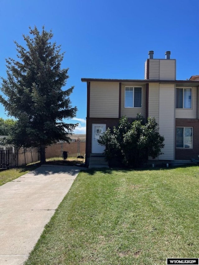 view of front of home with entry steps, a chimney, a front yard, and fence