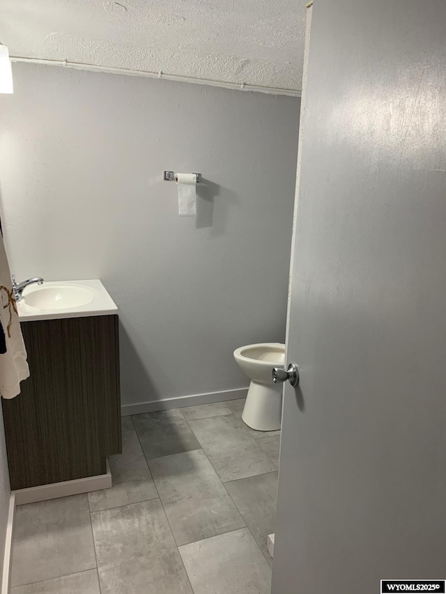 bathroom featuring toilet, baseboards, and vanity