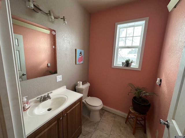 half bath with toilet, baseboards, and vanity