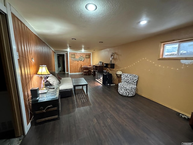 living room featuring a textured ceiling, baseboards, and wood finished floors