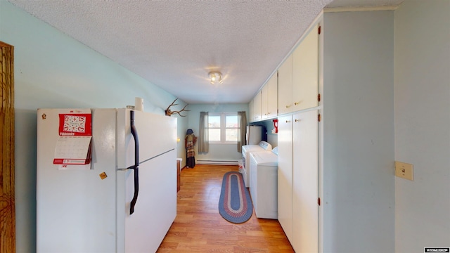 kitchen featuring light wood finished floors, white cabinets, washing machine and clothes dryer, freestanding refrigerator, and light countertops