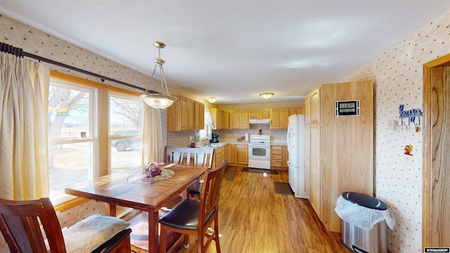 dining space with wallpapered walls and light wood finished floors