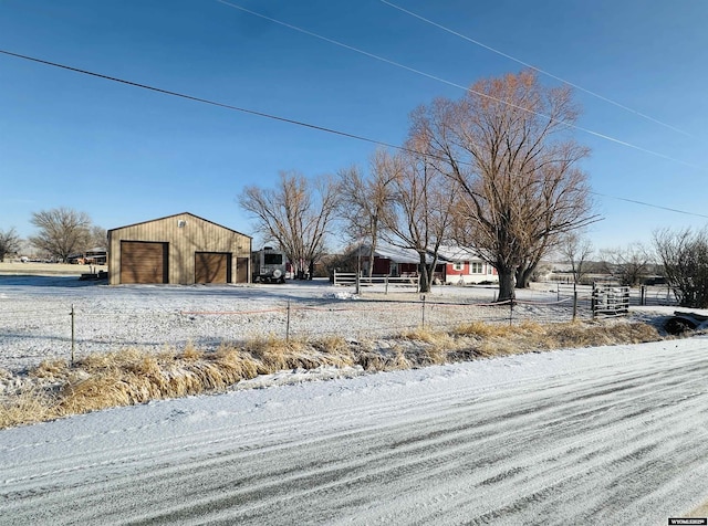 yard covered in snow featuring a garage, an outbuilding, and fence