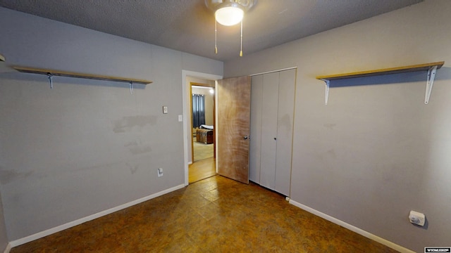 unfurnished bedroom featuring a closet, ceiling fan, a textured ceiling, and baseboards