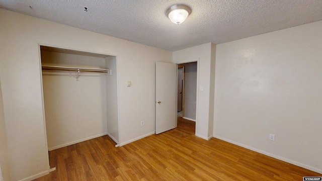 unfurnished bedroom with a textured ceiling, a closet, light wood-type flooring, and baseboards