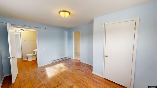 unfurnished bedroom featuring a baseboard heating unit, light wood-style floors, baseboards, and ensuite bathroom