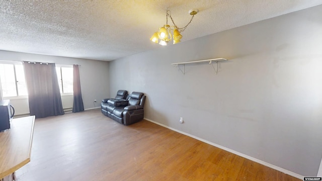 unfurnished room with a textured ceiling, wood finished floors, and baseboards