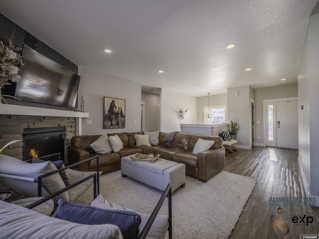 living room with baseboards, wood finished floors, a textured ceiling, a fireplace, and recessed lighting