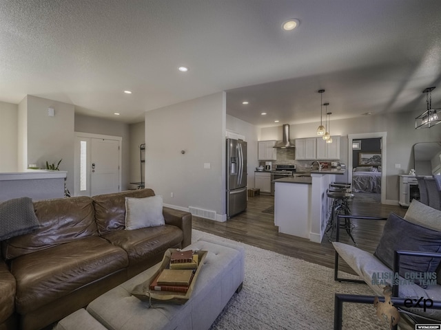 living area featuring dark wood-style floors, recessed lighting, visible vents, a textured ceiling, and baseboards